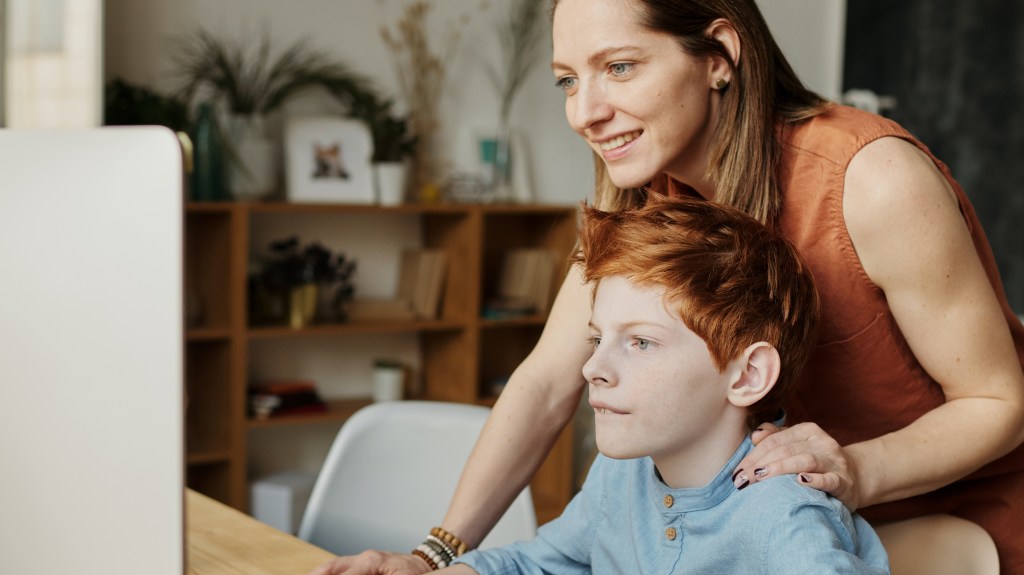 An adult helping a child navigate on the computer